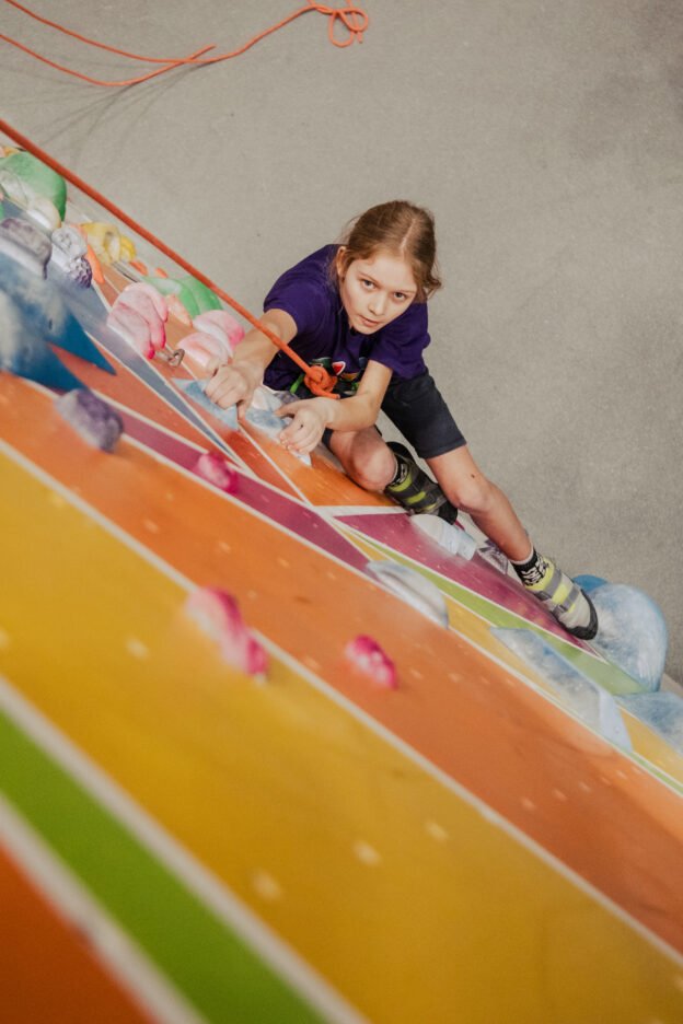 Girl climbing on a colourful climbing wall