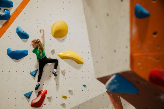 girl climbing on the climbing wall with colourful climbing holds