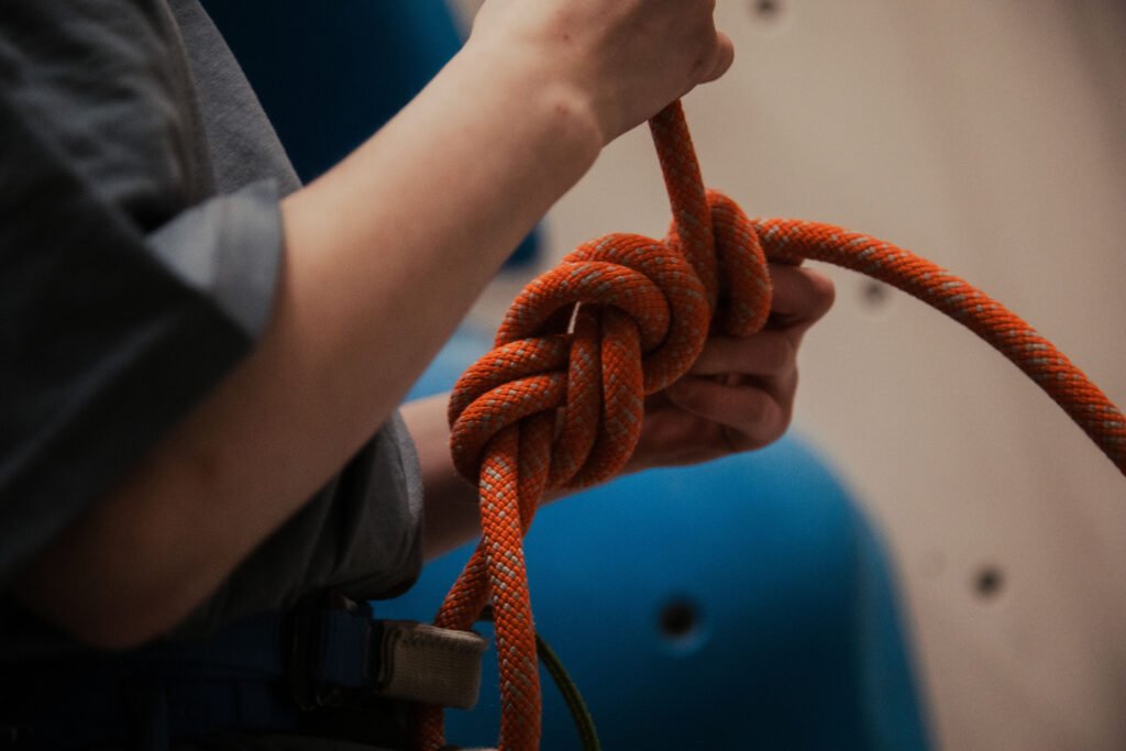 Tying a climbing knot picture of orange rope and hands